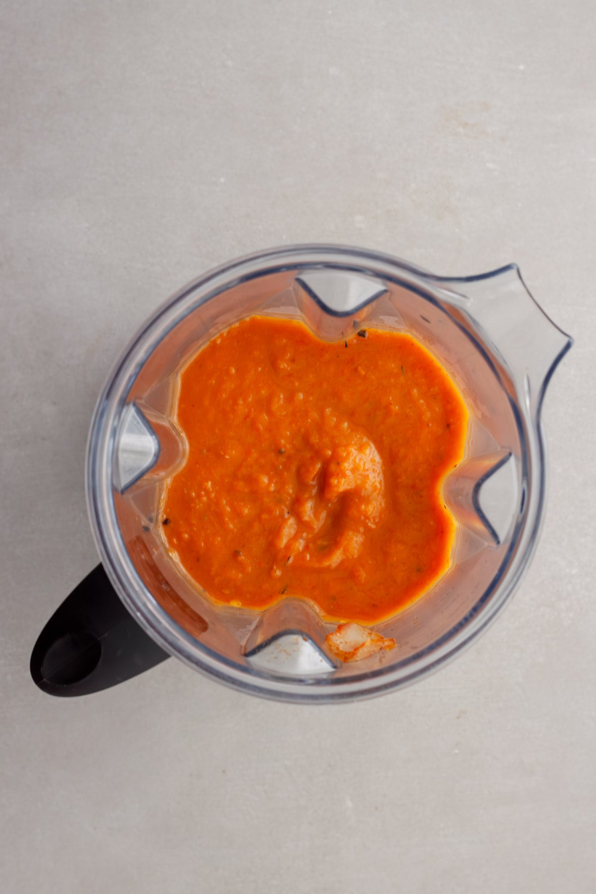 A blender with butternut squash and red pepper soup pureed until smooth.