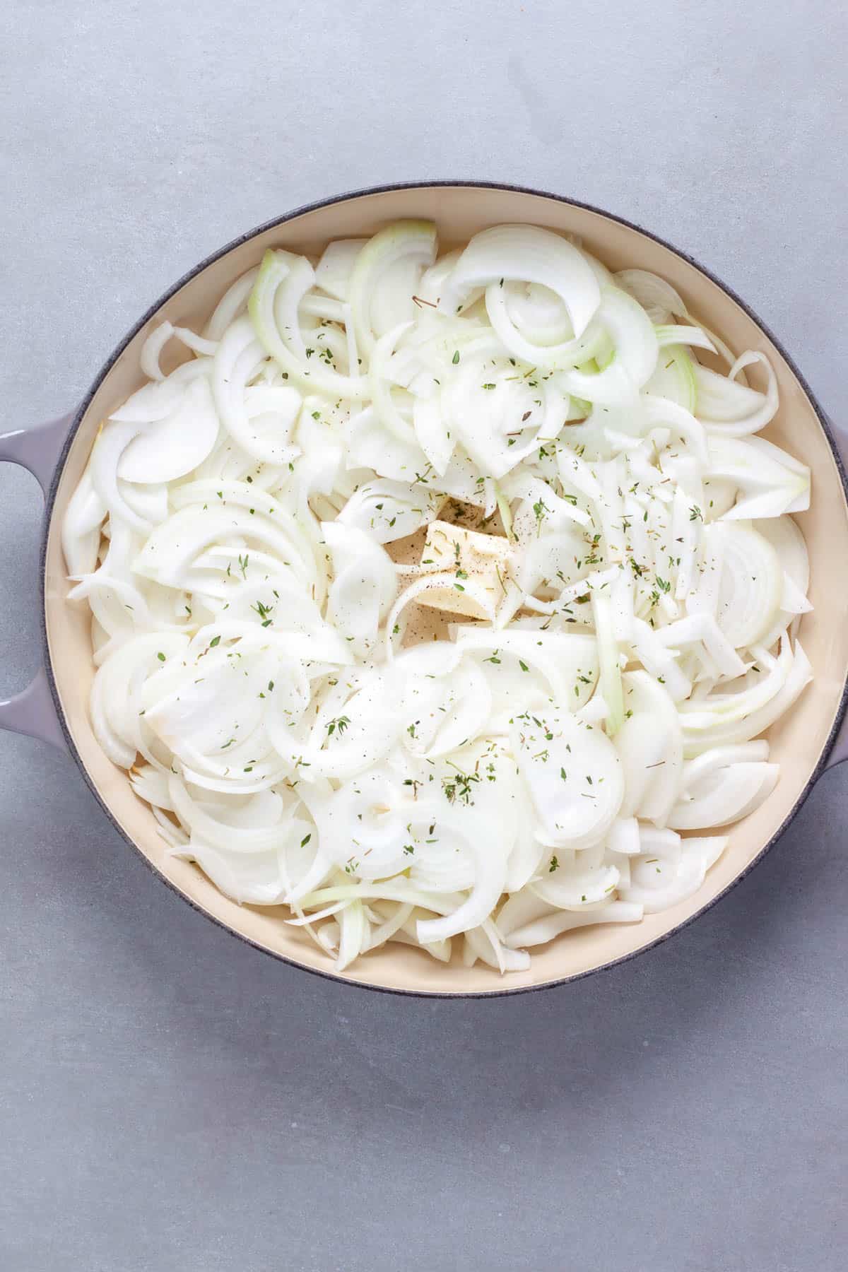 Sliced onions in a pan ready to get cooked for caramelized onions.