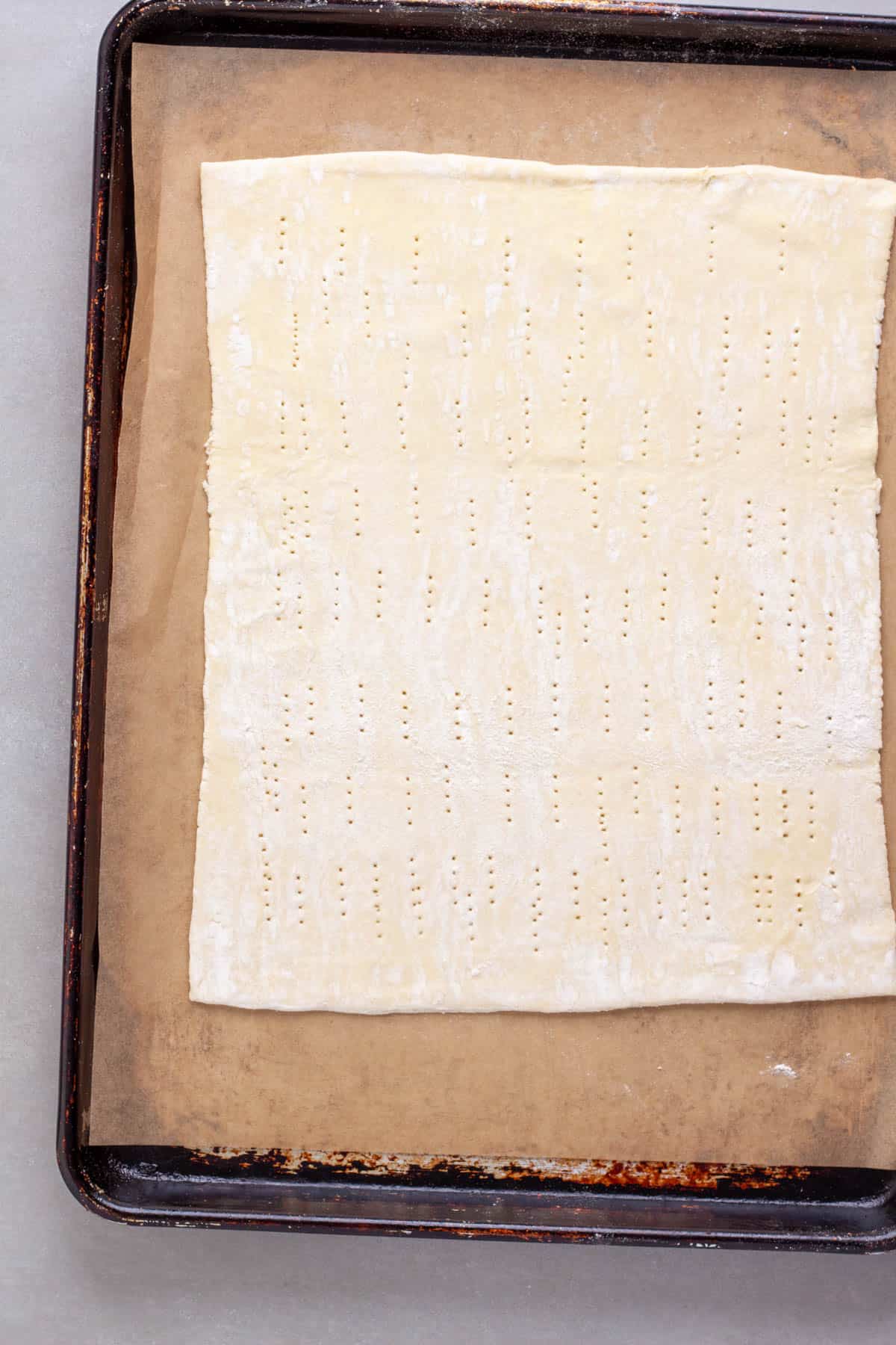 Puff pastry on a cutting board with little holes poked in by a fork.