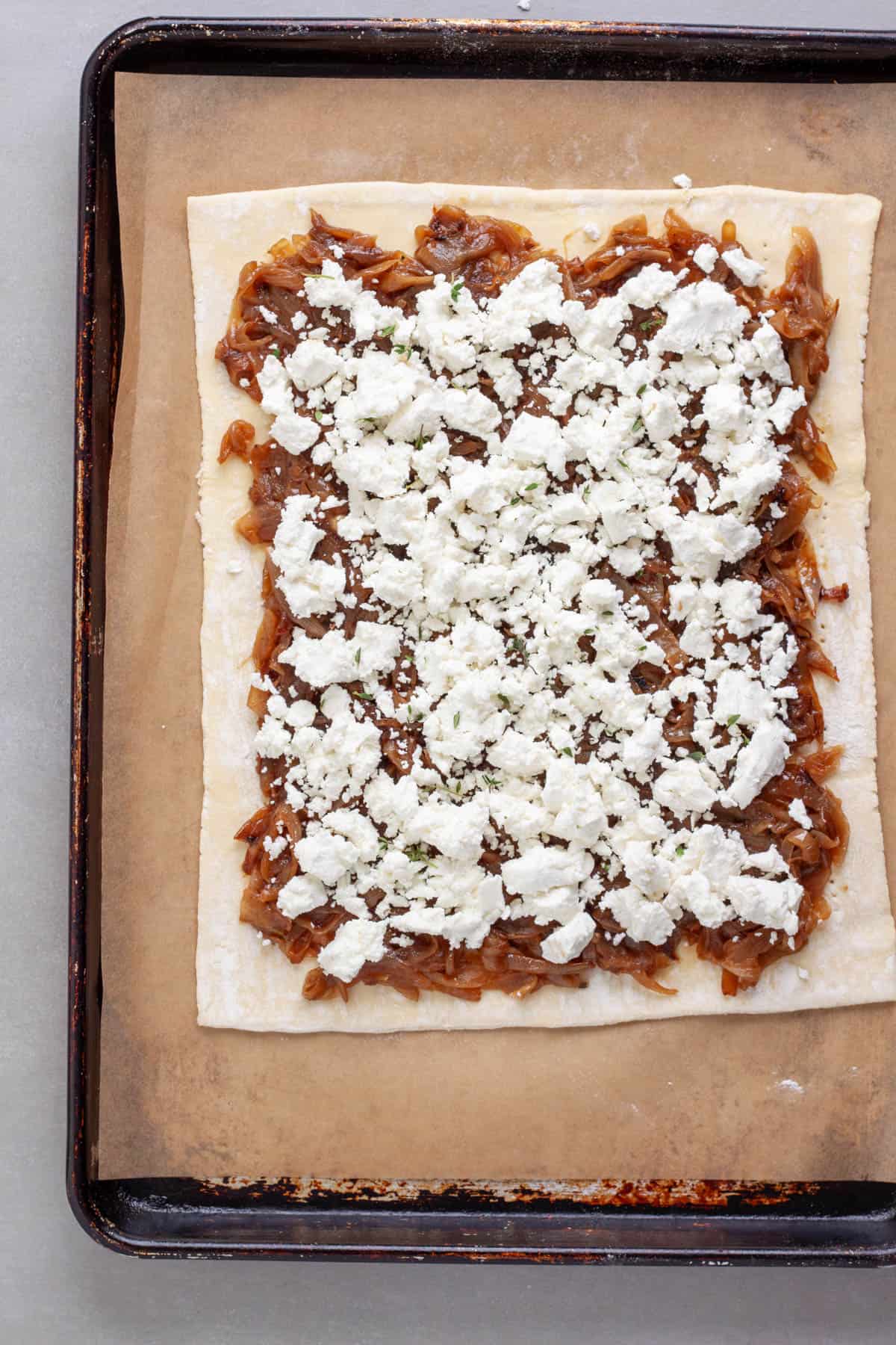 Goat cheese spread on top of caramelized onions all on a rolled out sheet of puff pastry.