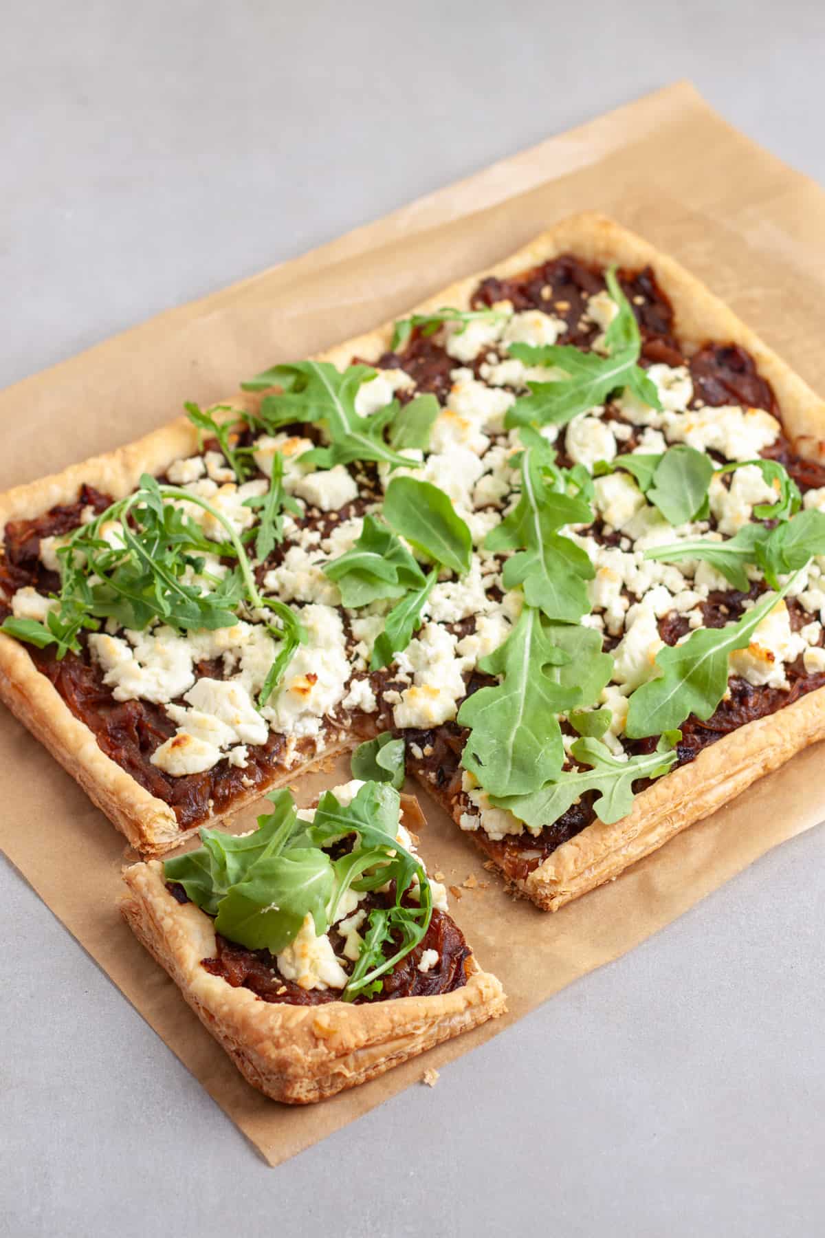 A portion of caramelized onion and goat cheese tart cut out of a larger tart.