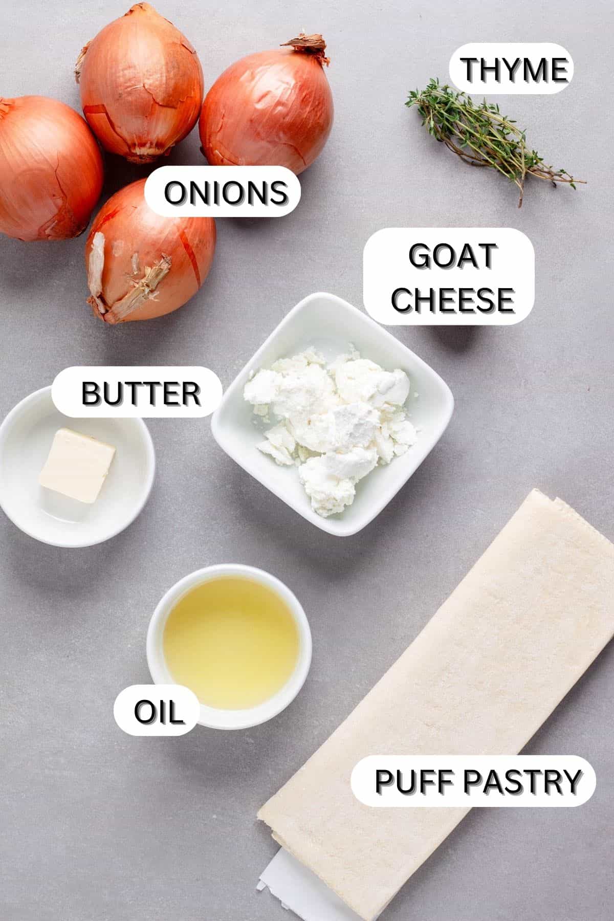 Ingredients for caramelized onion and goat cheese tart on a gray table.