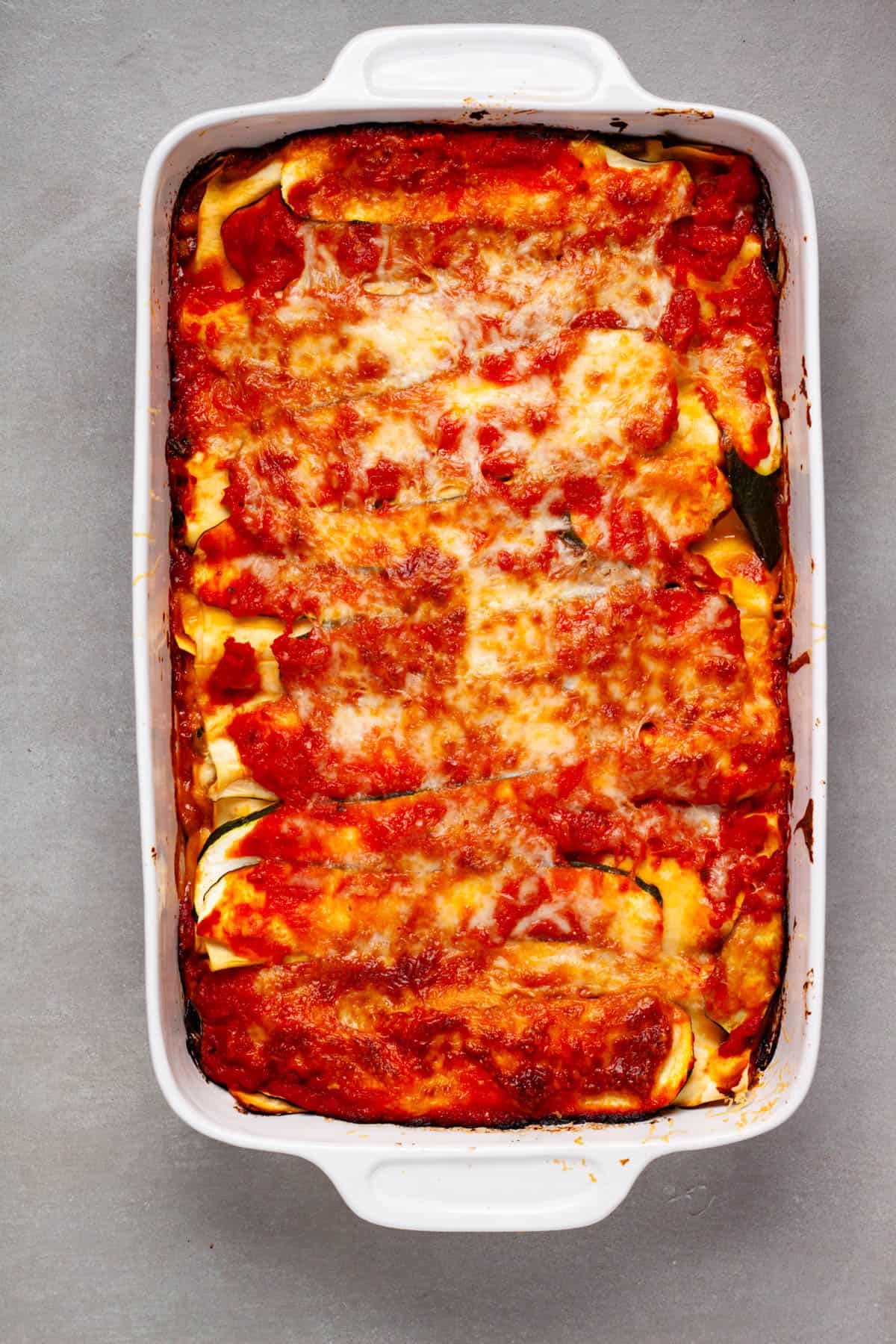 A bubbly and cheesy vegetable lasagna in a white baking dish.