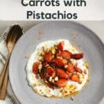 A bowl of yogurt topped with sauteed spiced carrots and pistachios.