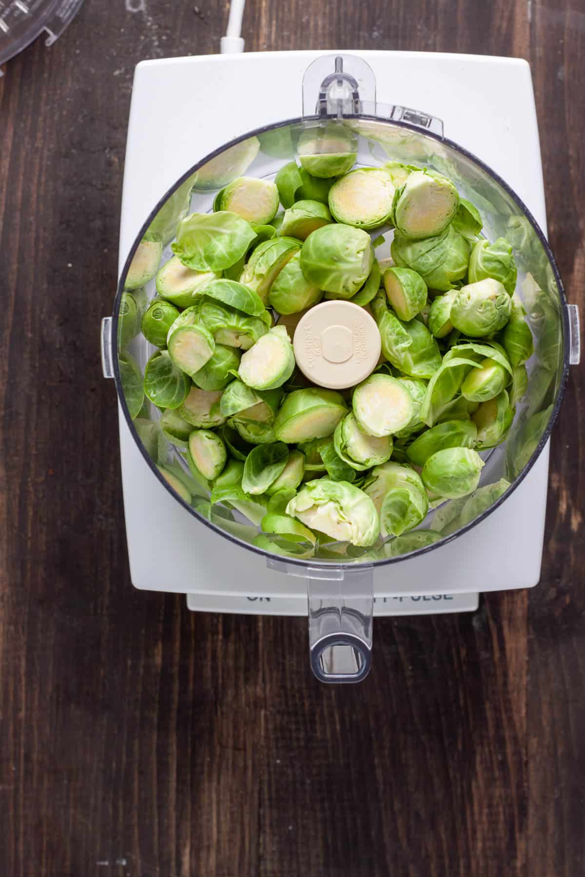 Halved brussels sprouts in the base of a food processor.