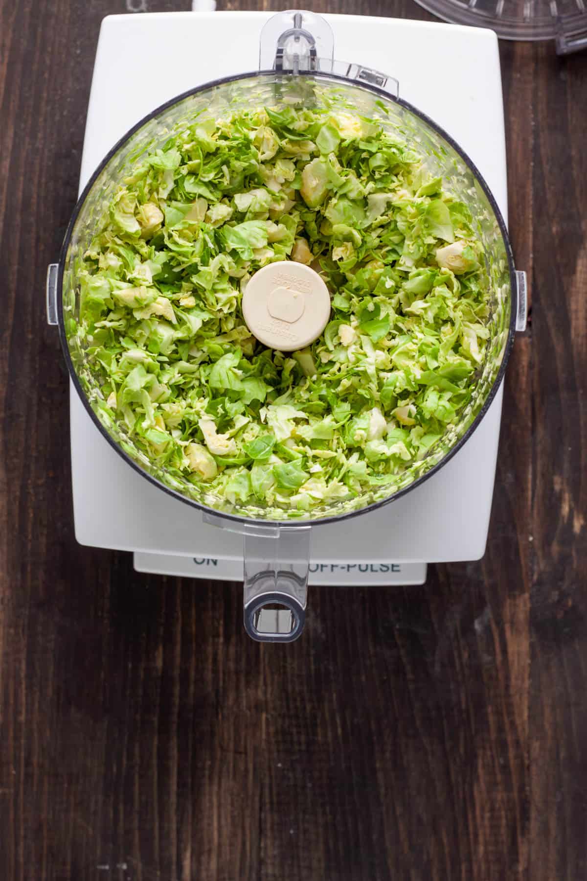 Shredded brussels sprouts in the base of a food processor.