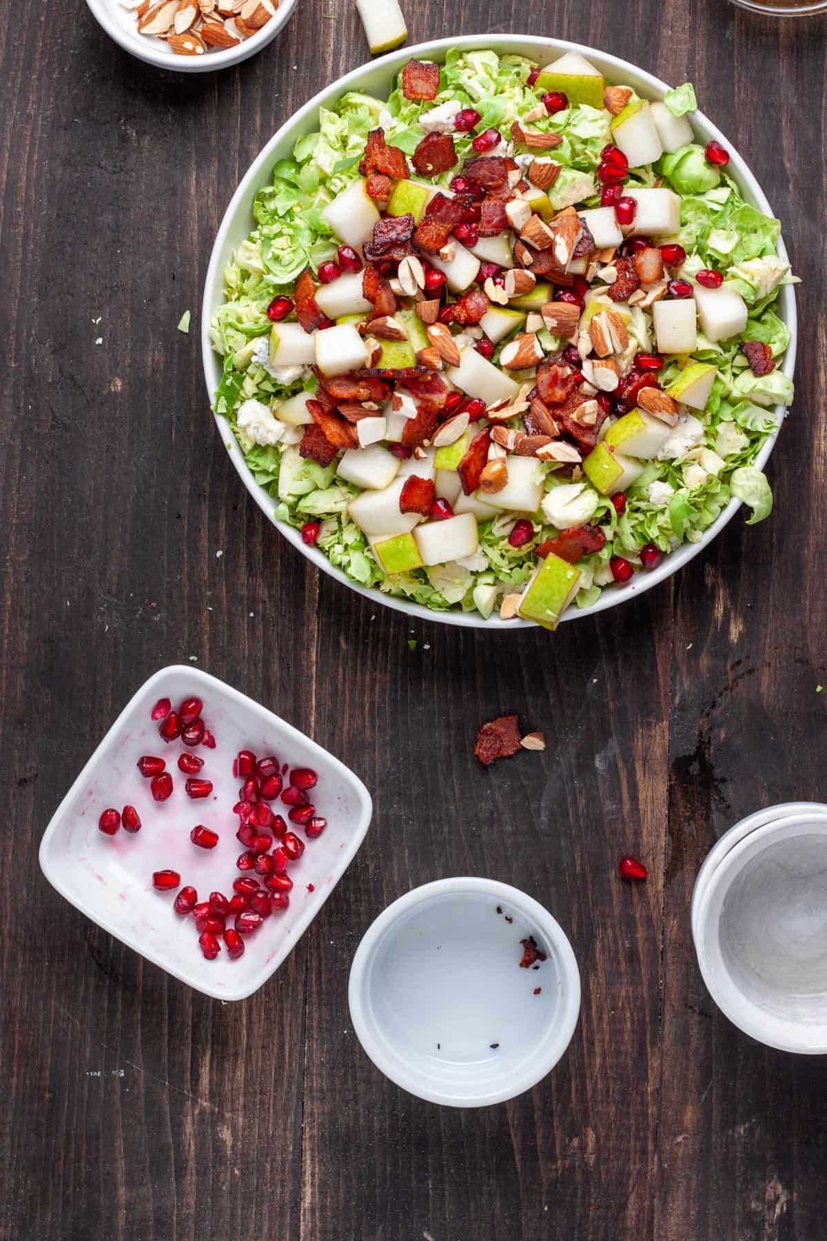 A shaved brussels sprouts with bacon and fig dressing getting assembled in a serving bowl.