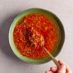 A green bowl with a red spicy chili-lemongrass sauce.