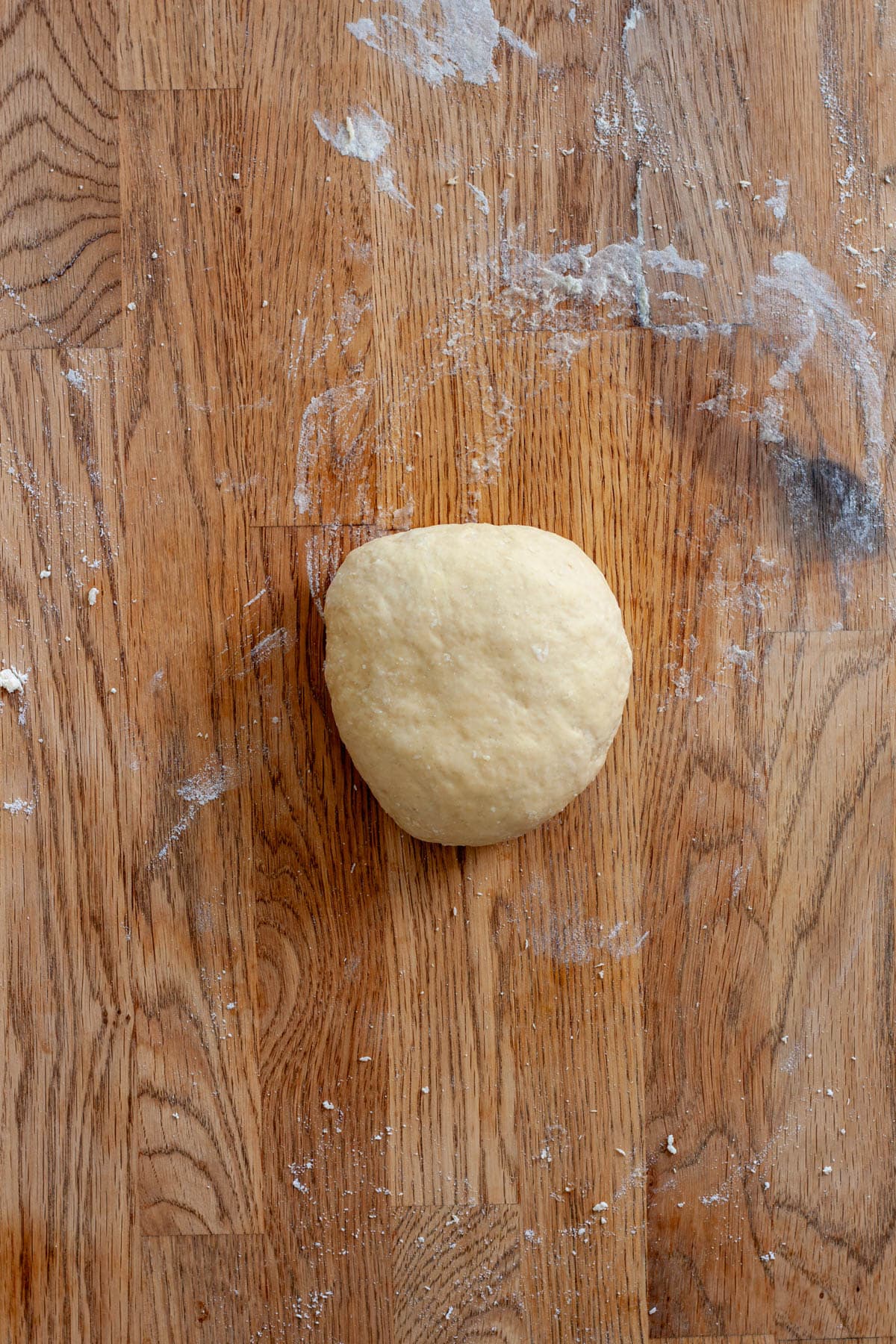 A ball of fresh homemade pasta dough on a butcherblock countertop.
