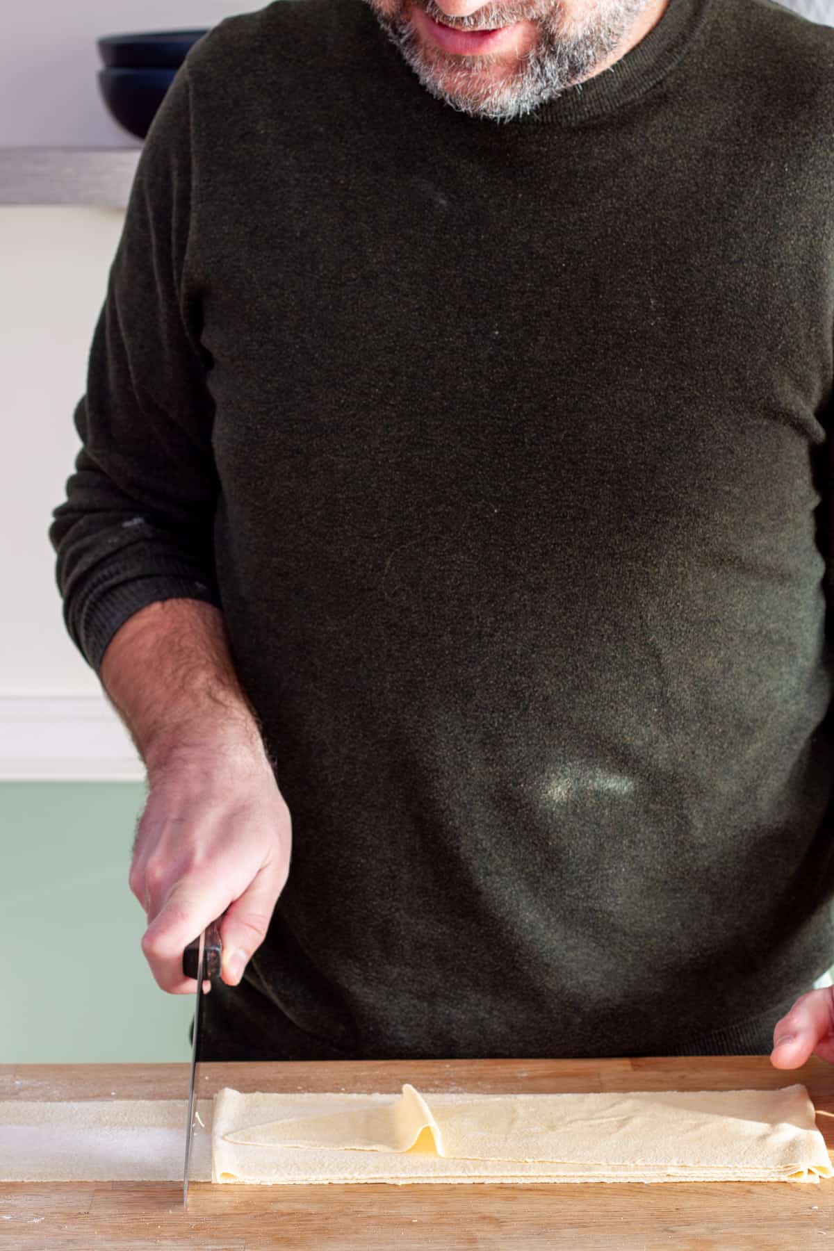 Sheets of fresh pasta getting cut into rectangles.
