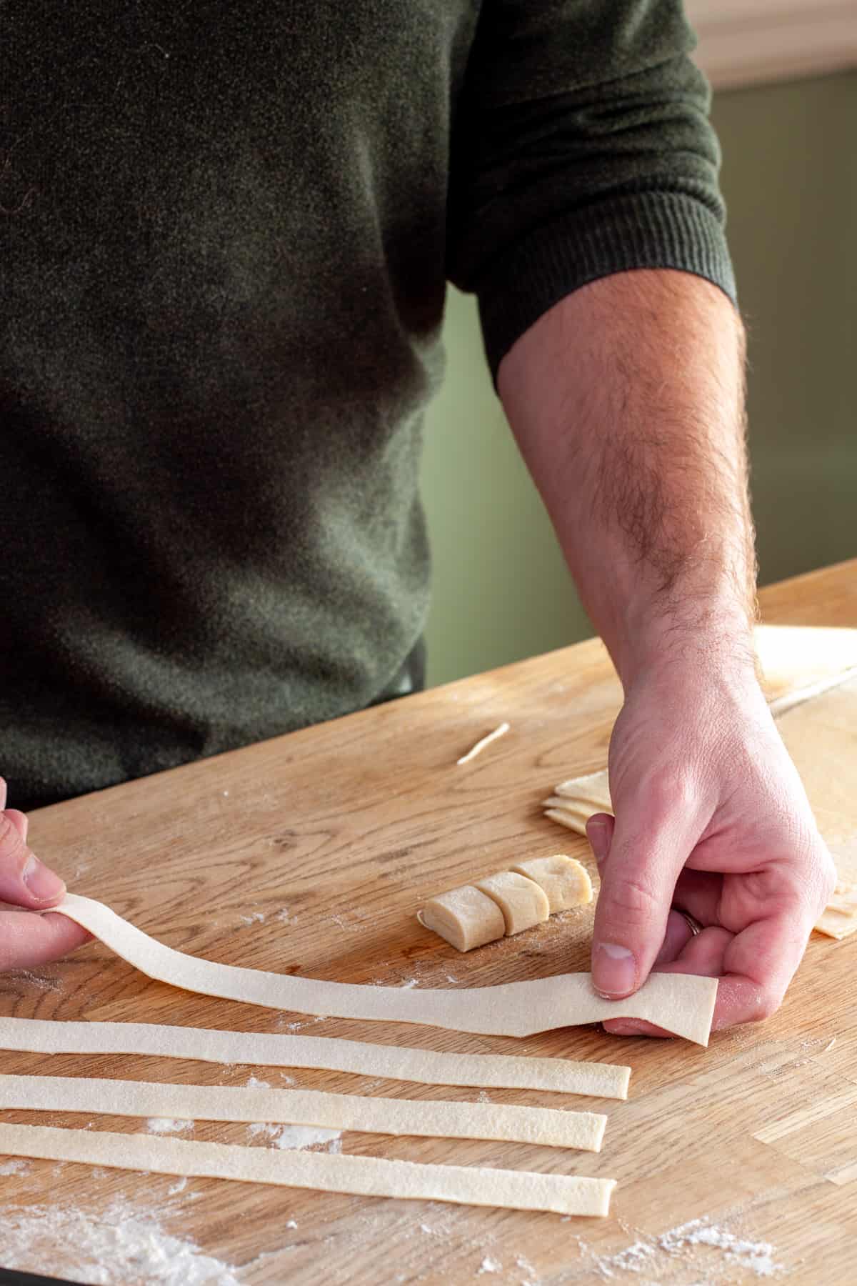 Strips of homemade fresh pasta getting stretched.