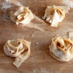 Nests of fresh homemade pasta on a butcherblock countertop.