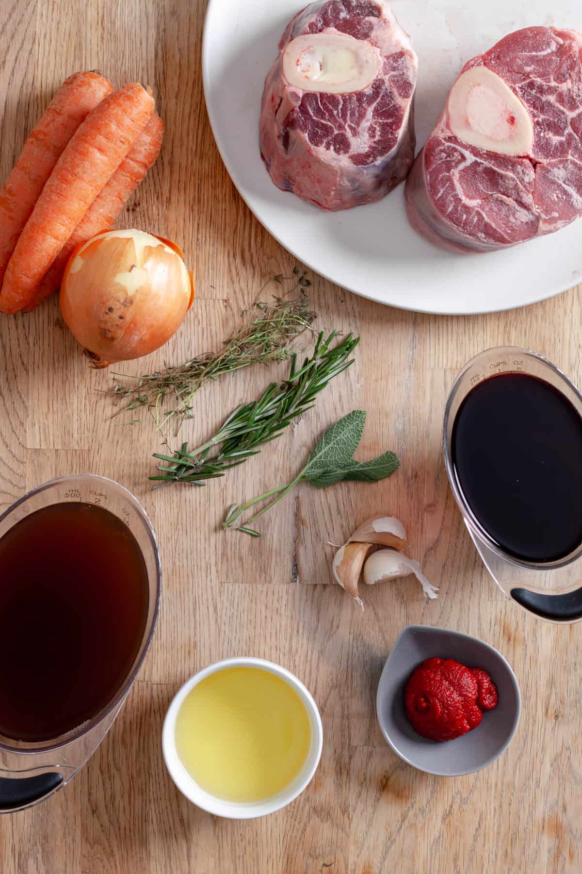 Ingredients for braised beef shanks on a butcherblock cutting board.