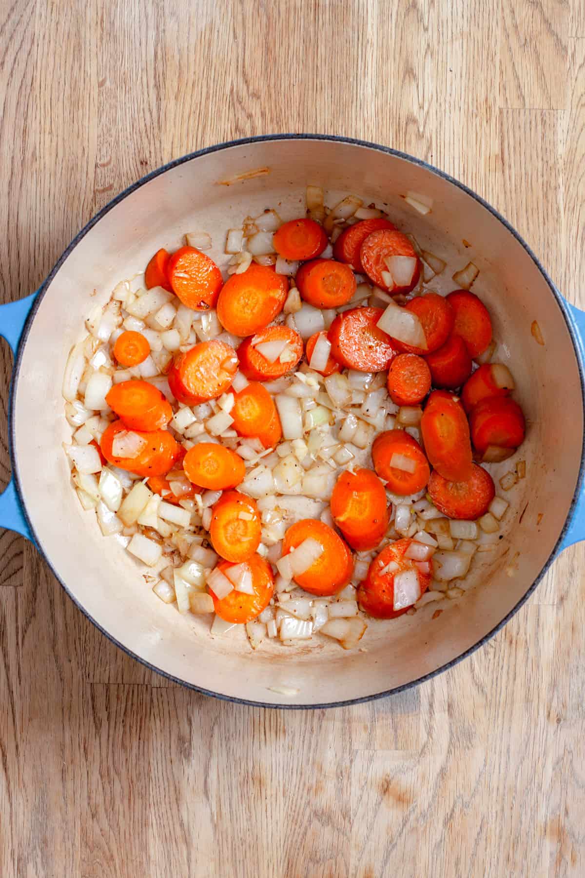 Onions and carrots sautéing in a dutch oven.