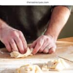 A nest of homemade fresh pappardelle getting turned together on a cutting board.