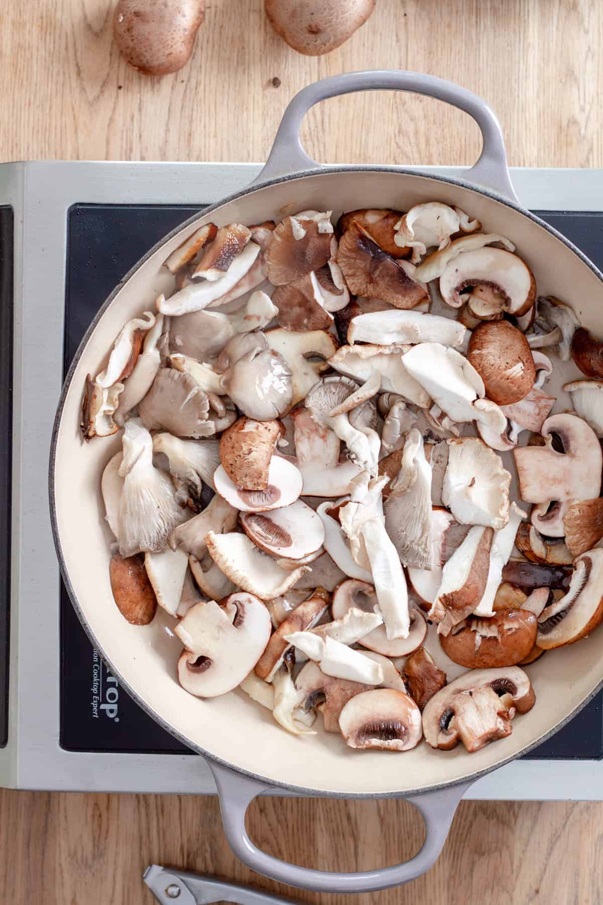 Various sliced mushrooms cooking in a large skillet for homemade mushroom pappardelle.