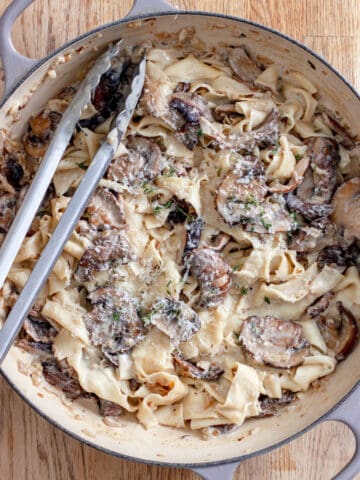 A large skillet of mushroom pappardelle with grated parmesan on top.