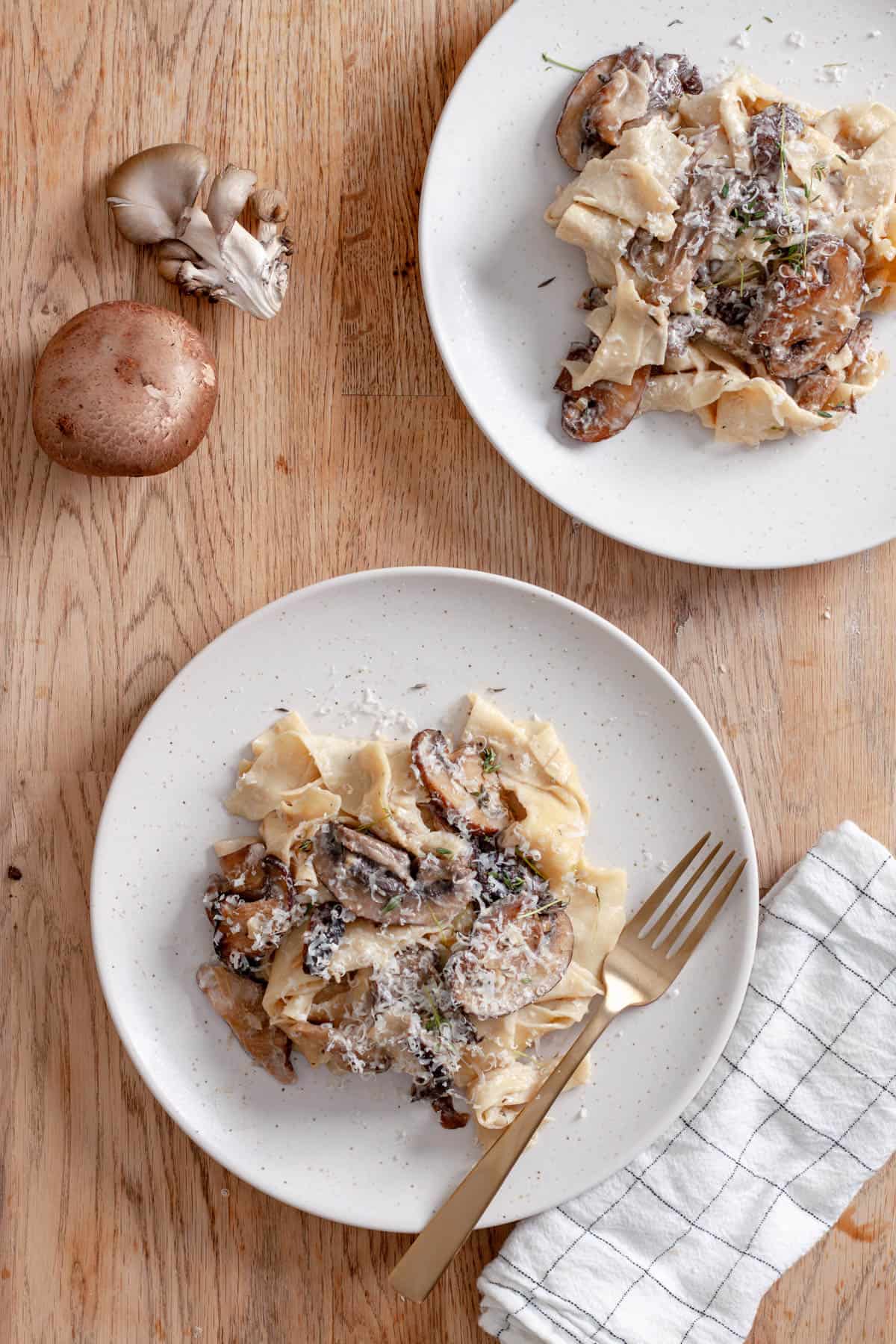 Two servings of mushroom pappardelle on white plates.