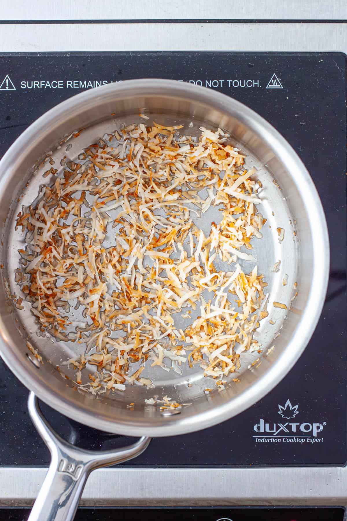 Shredded coconut toasting in a medium saucepan.