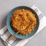 A green bowl filled with golden-grown crispy quinoa.
