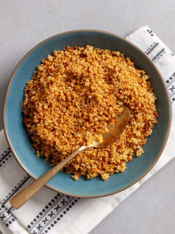 A green bowl filled with golden-grown crispy quinoa.