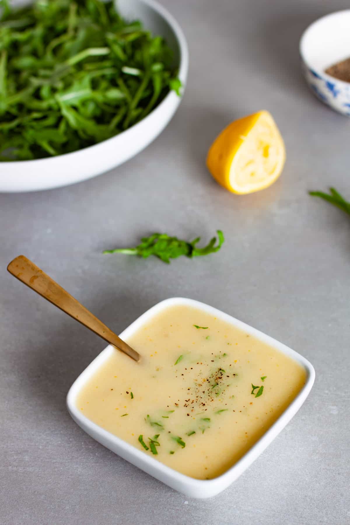 A small white bowl of preserved lemon vinaigrette topped with chopped parsley.