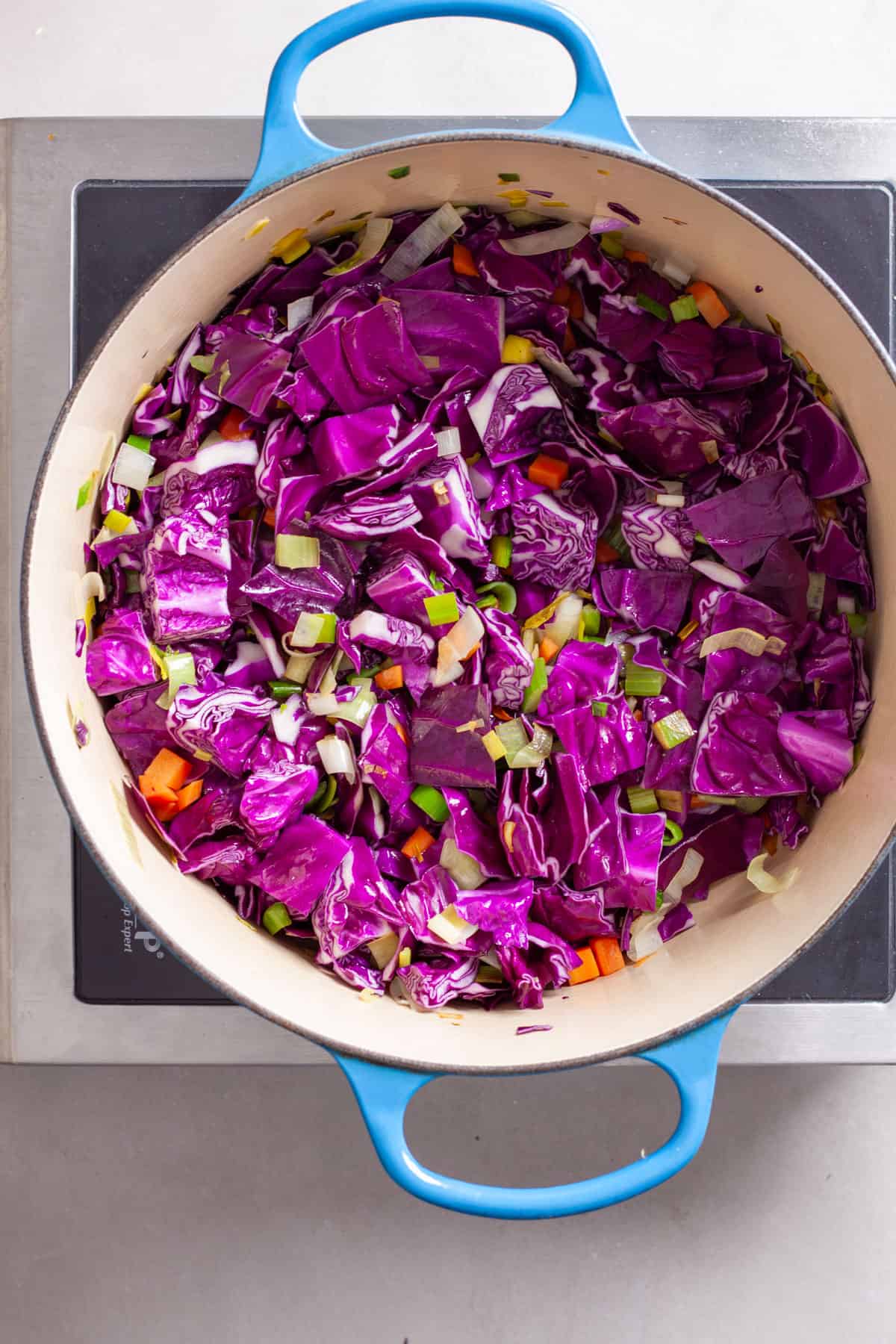 Red cabbage added to a dutch oven for a hearty red cabbage soup.