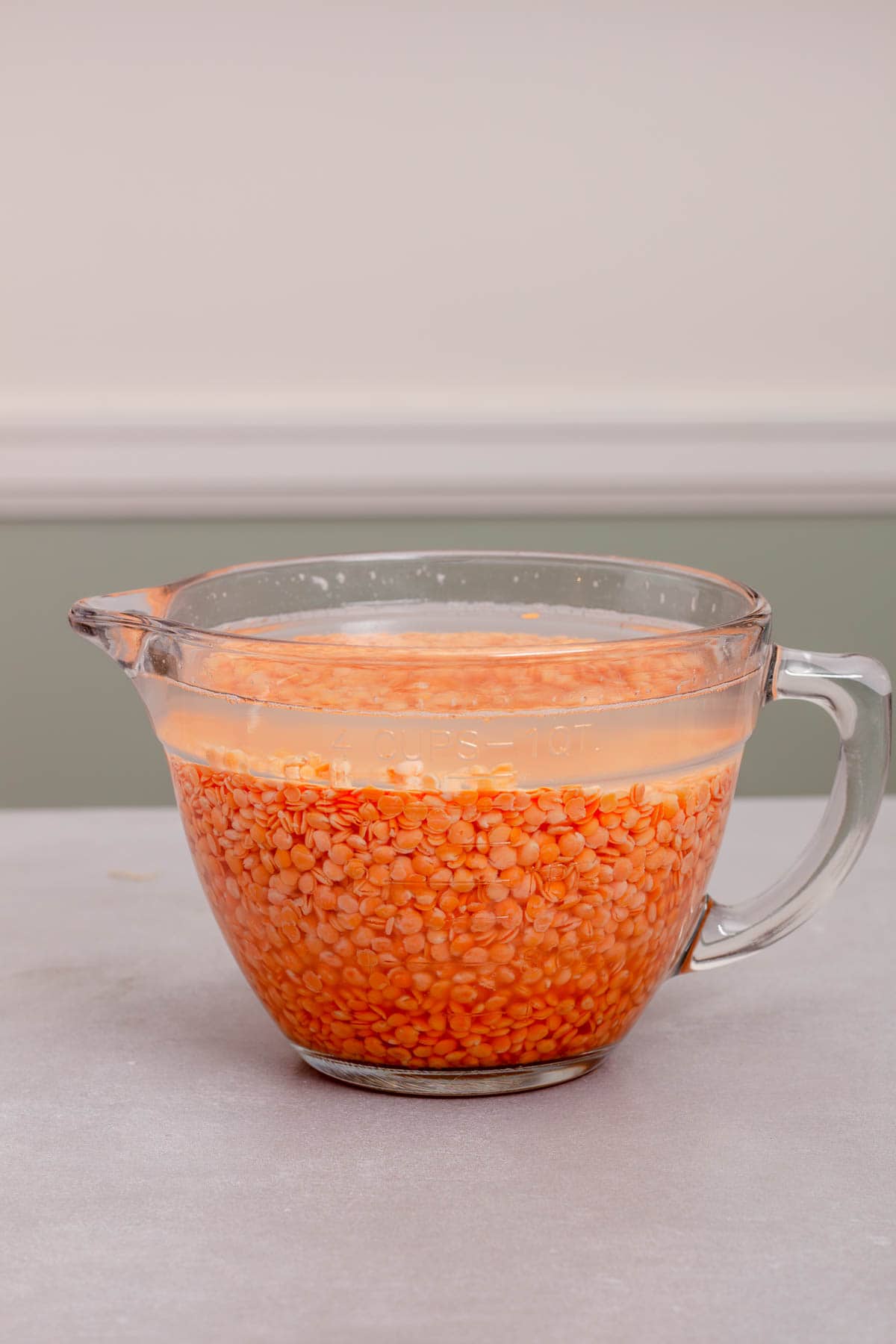 Red Lentils soaking in a large measuring cup of water.