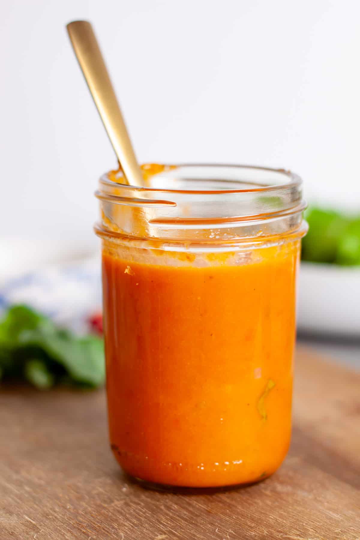 A mason jar with a vibrant red sun-dried tomato vinaigrette.