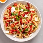 A large white bowl with homemade sun-dried tomato pasta salad on a gray table.