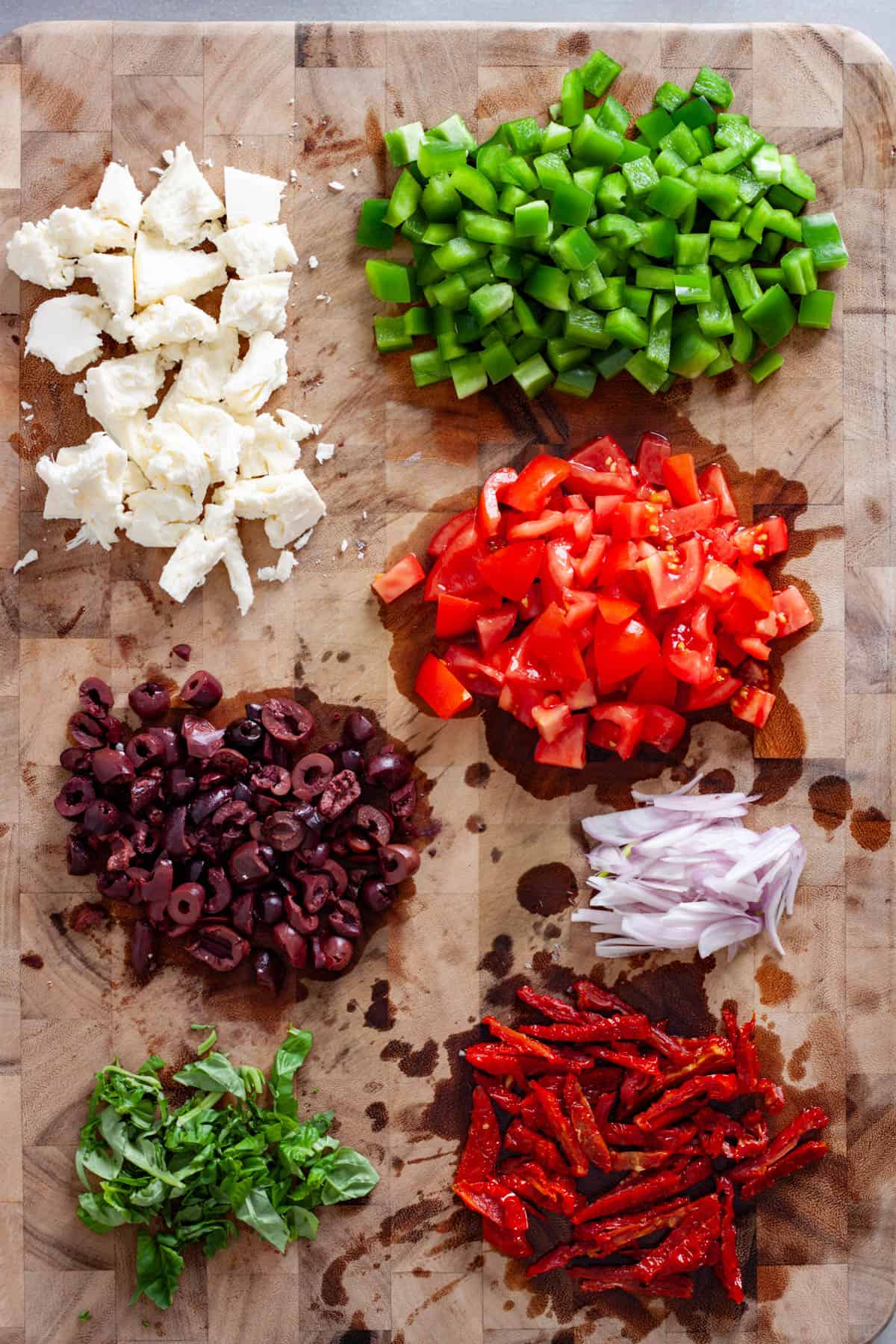 Vegetables, basil and mozzarella cheese chopped up on a cutting board.