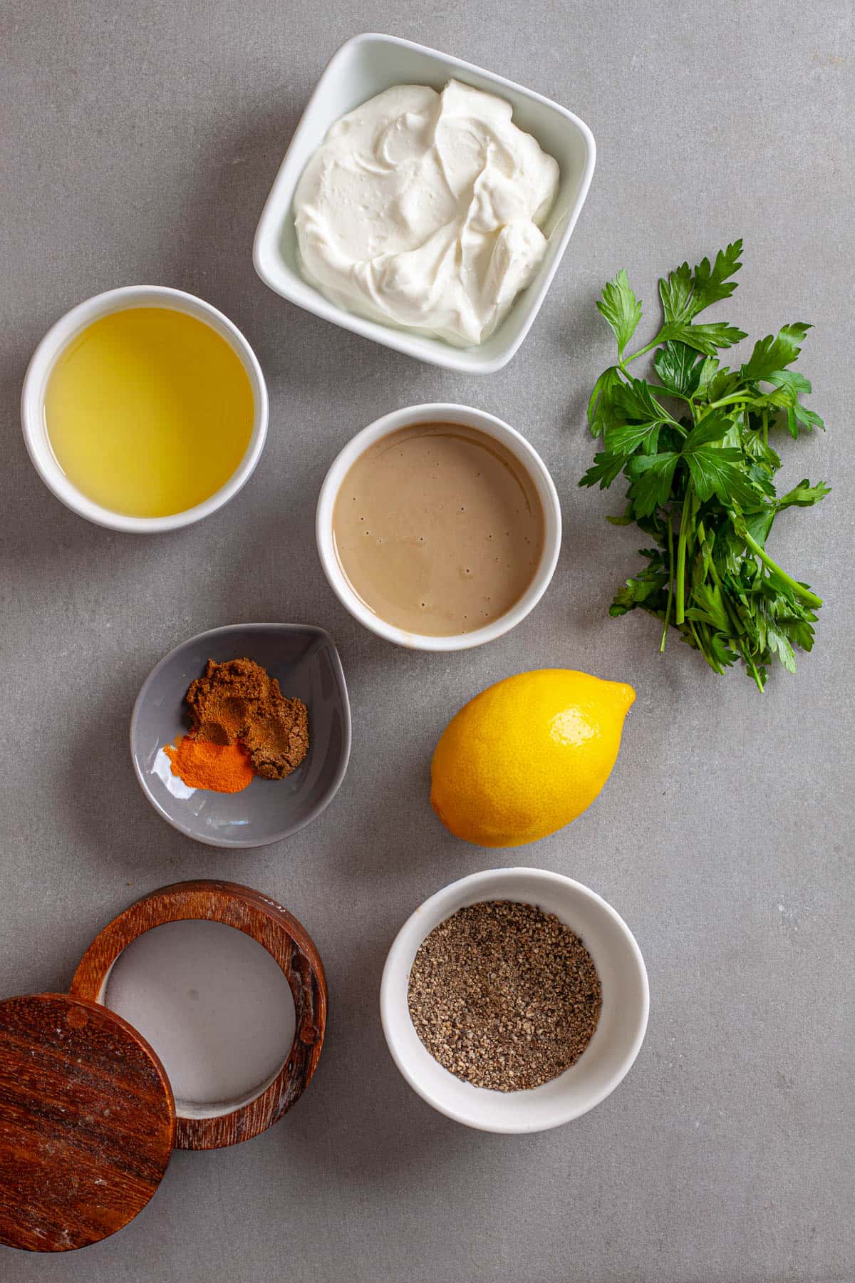 Ingredients for tahini yogurt sauce on a gray table.
