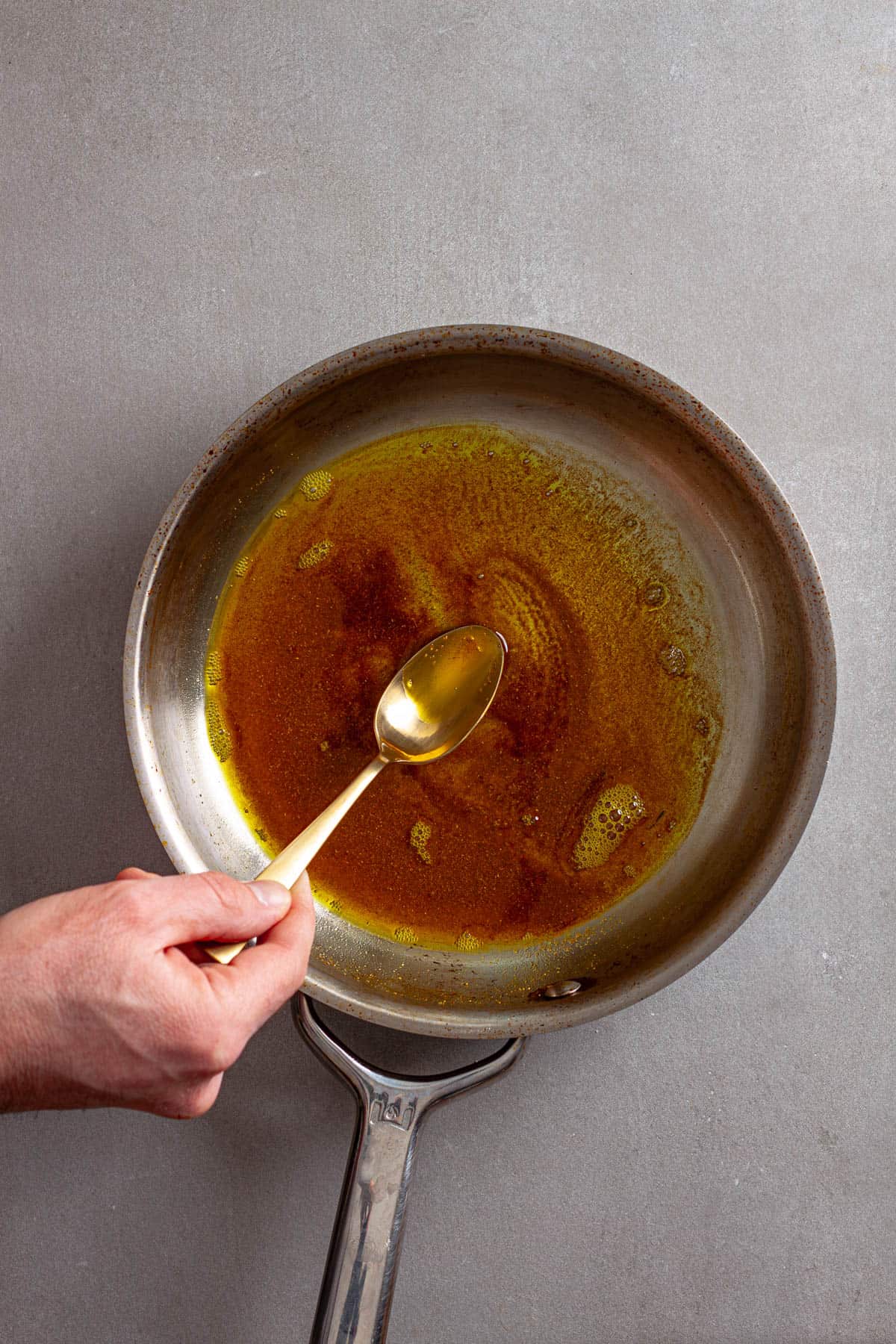 Spices cooking in olive oil in a small skillet.