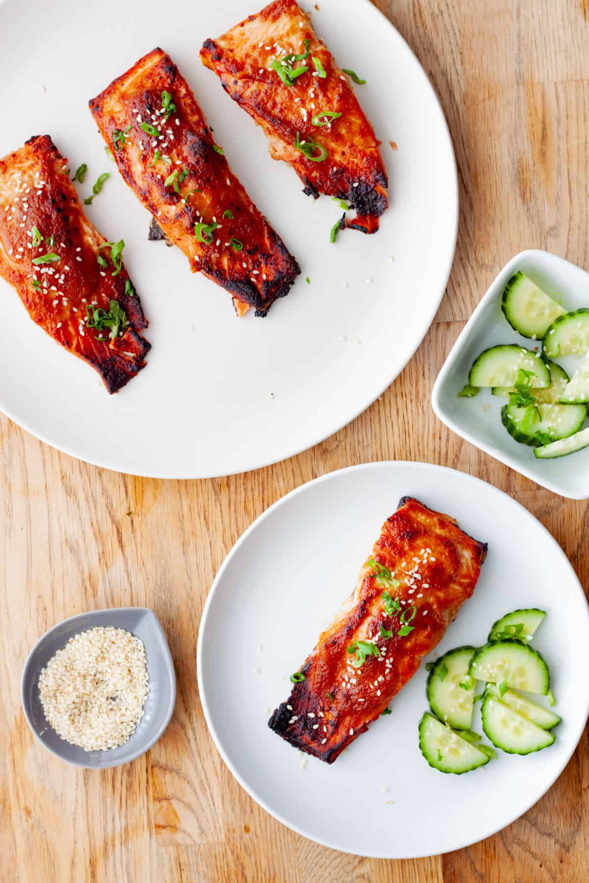 A platter of miso salmon with a serving of salmon on a small plate with cucumbers and sesame seeds.