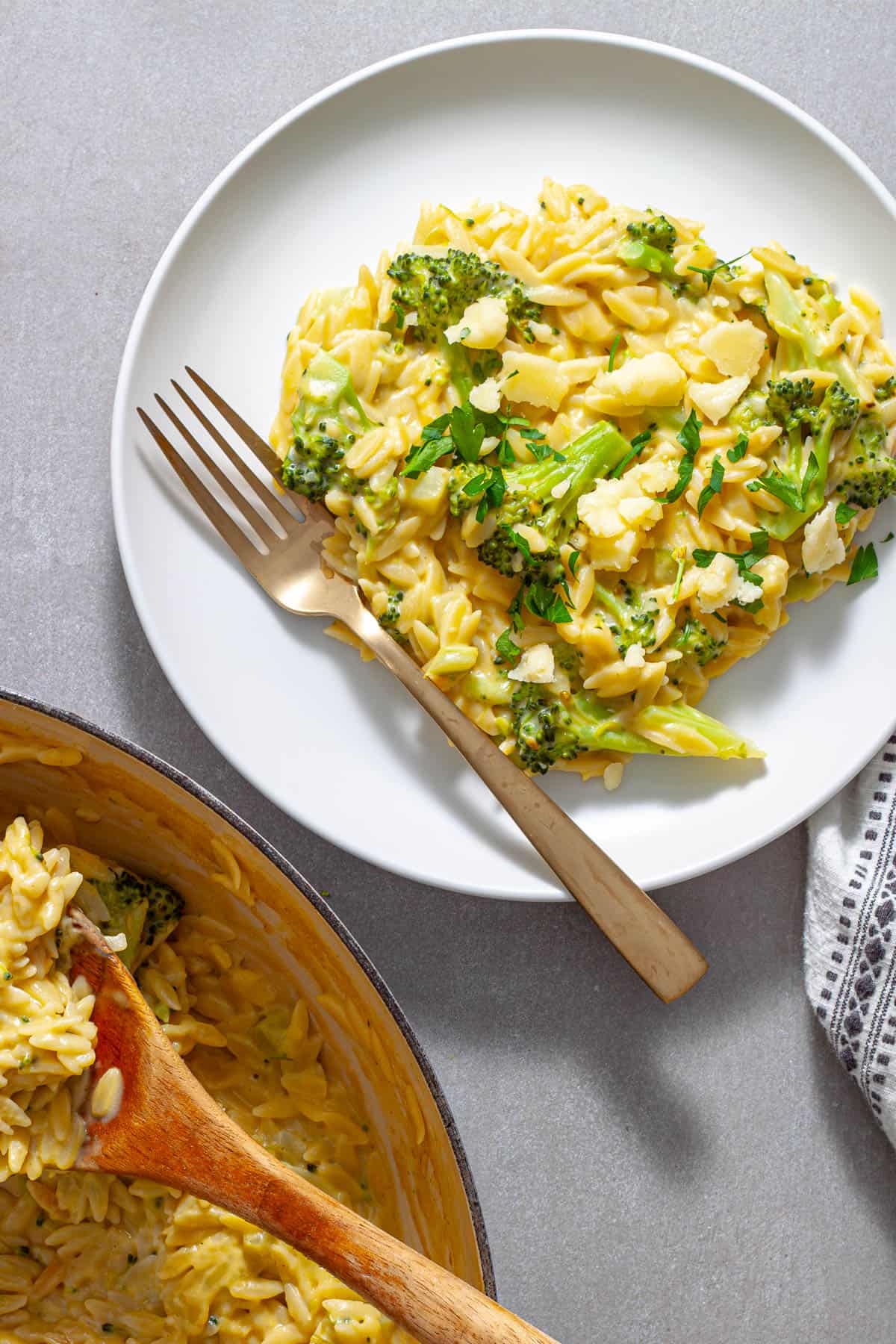A serving of creamy broccoli cheddar orzo on a white plate.