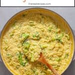 A pot of creamy broccoli orzo on a gray table.