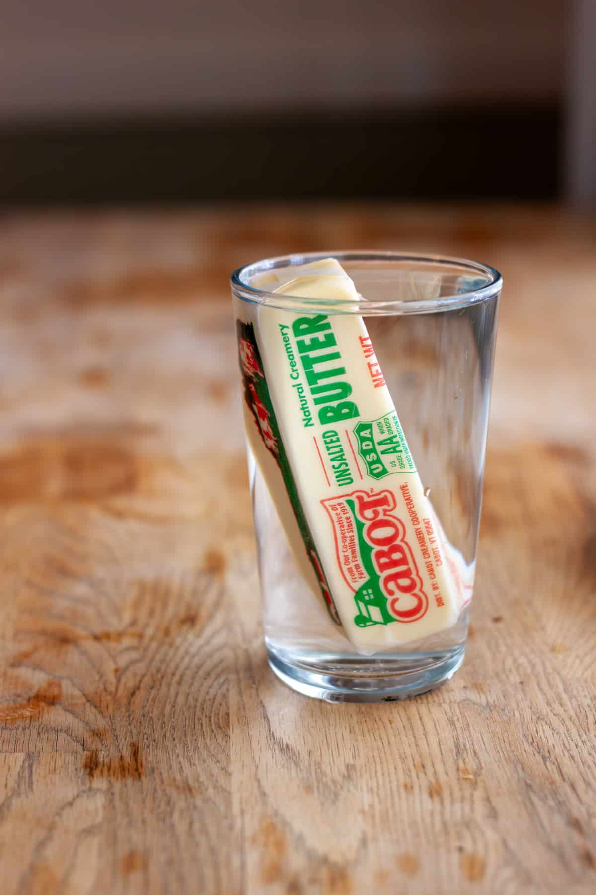 A stick of butter in a glass of warm water to help bring the butter to room temperature.