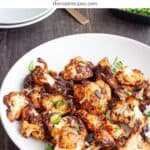 A platter of miso cauliflower topped with fresh herbs.