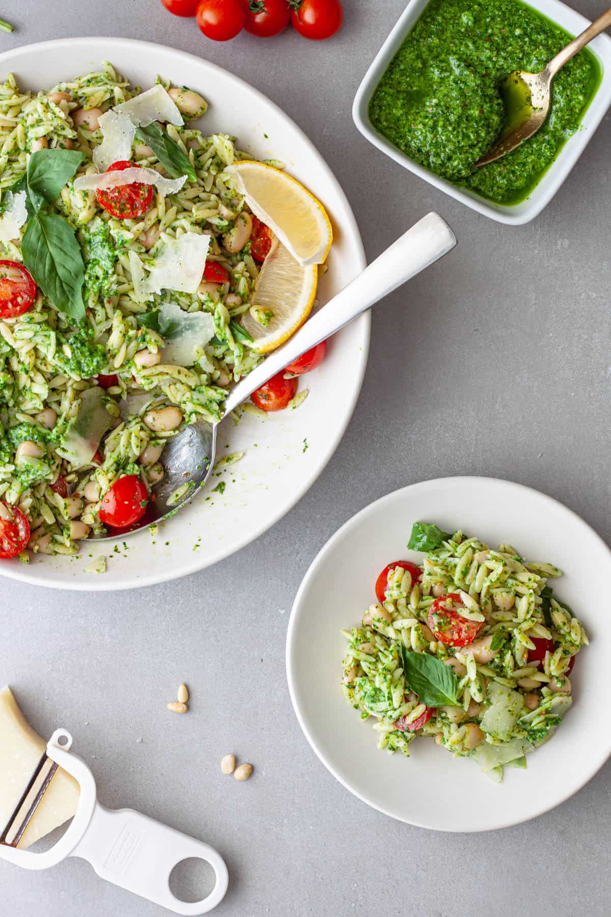 A small plate with orzo pesto and a large bowl with more of the pesto orzo off to the side.