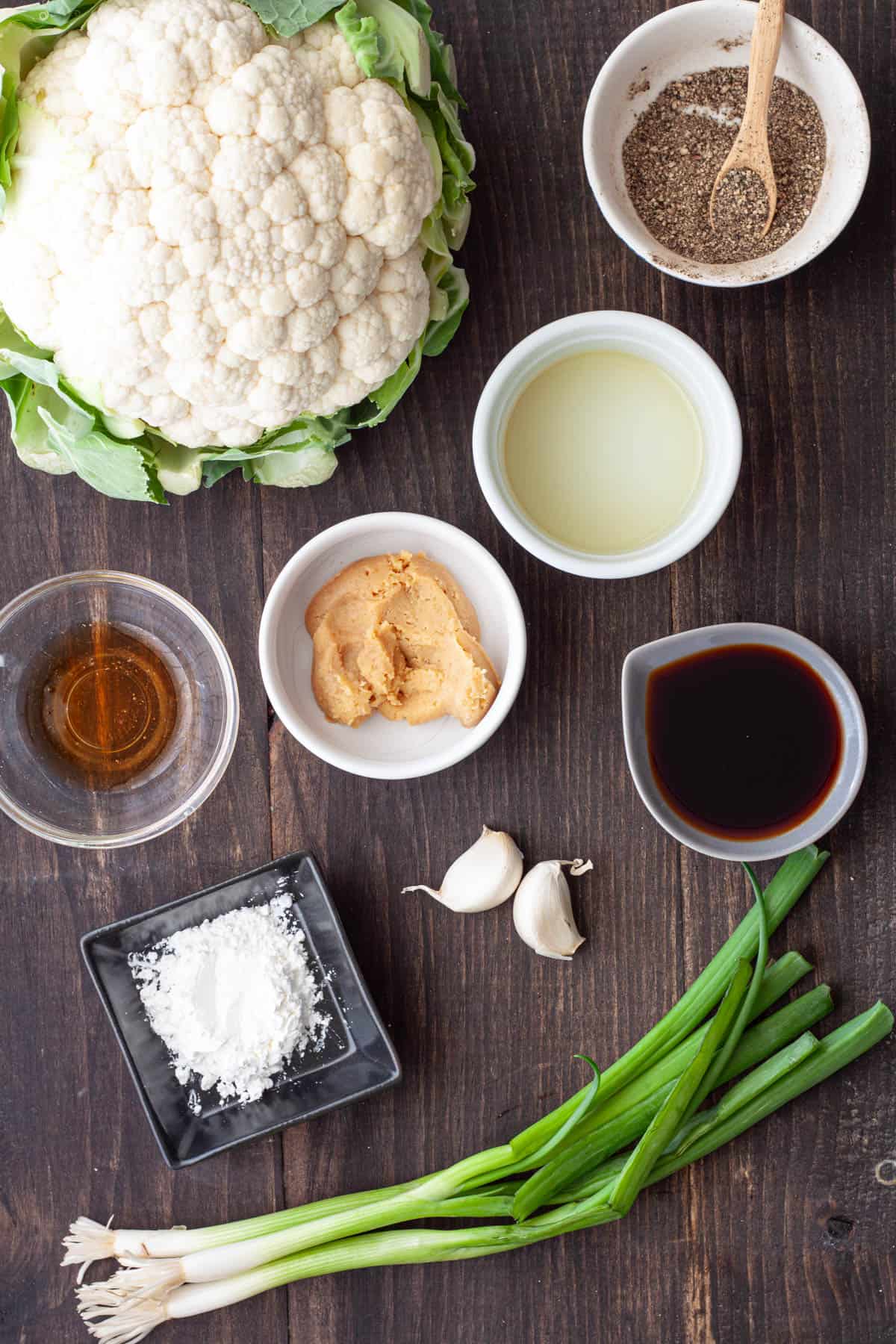 Ingredients for miso cauliflower on a dark table.