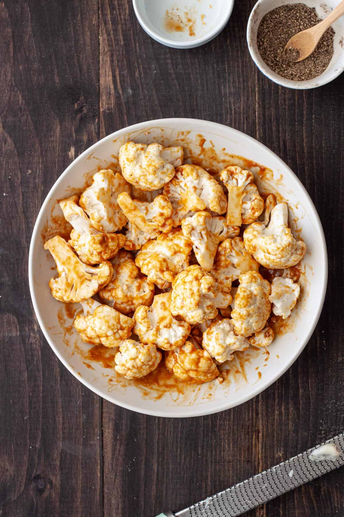 Cauliflower florets in a white bowl tossed in a miso marinade.