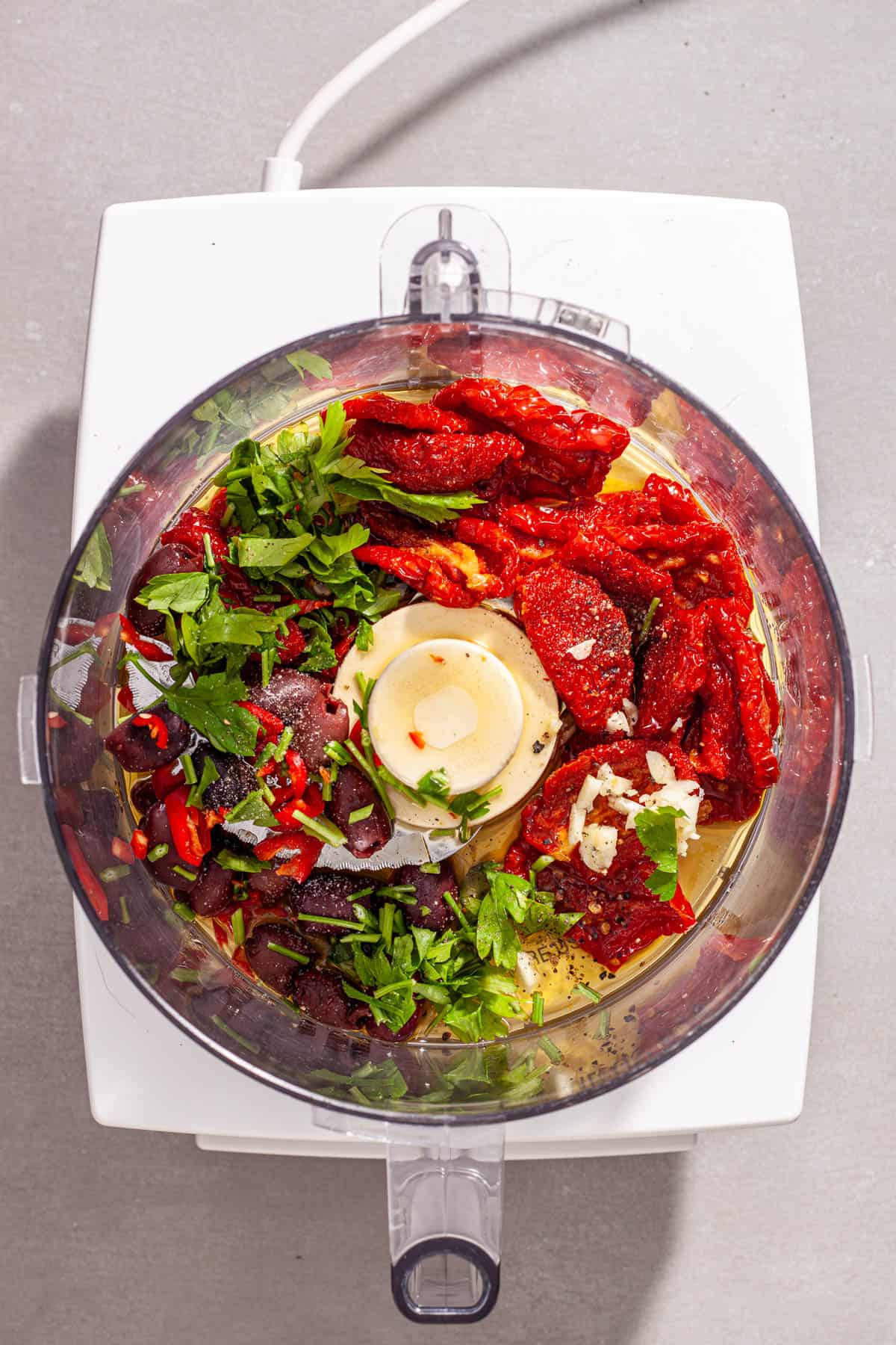 Ingredients for sun-dried tomato spread on a food processor ready to get chopped.