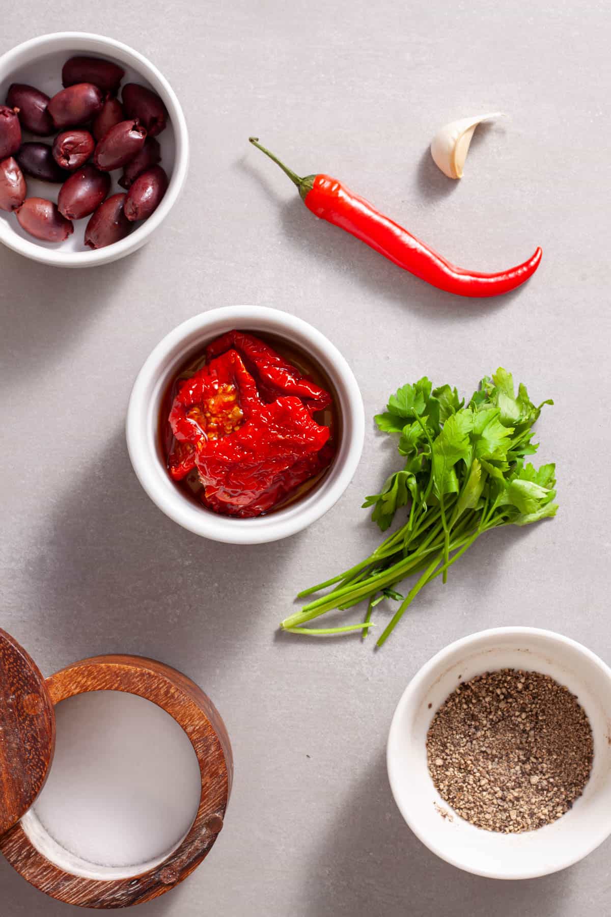 Ingredients for homemade sun-dried tomato spread on a gray table.