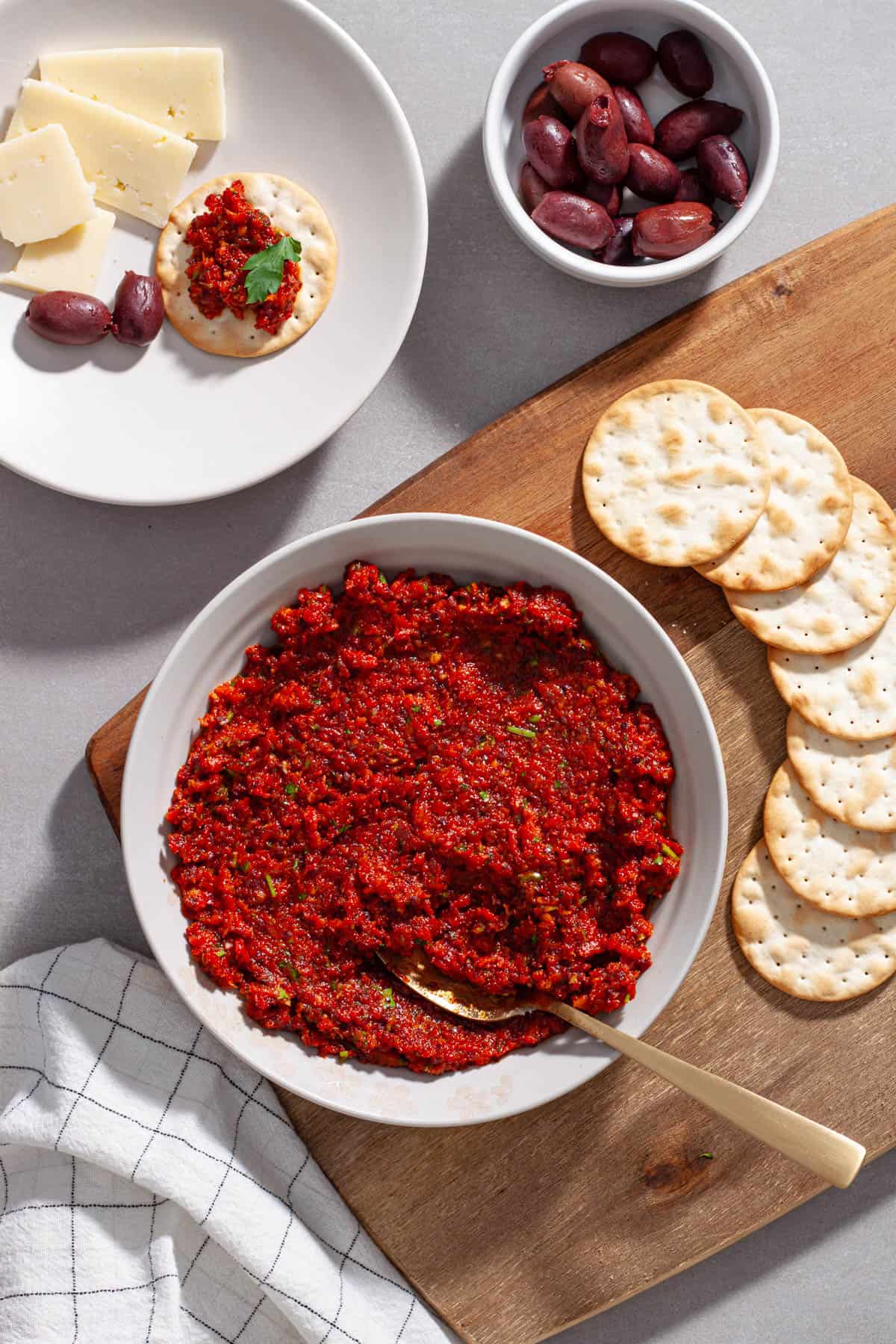 A cheese board with sun-dried tomato spread on a cutting board.