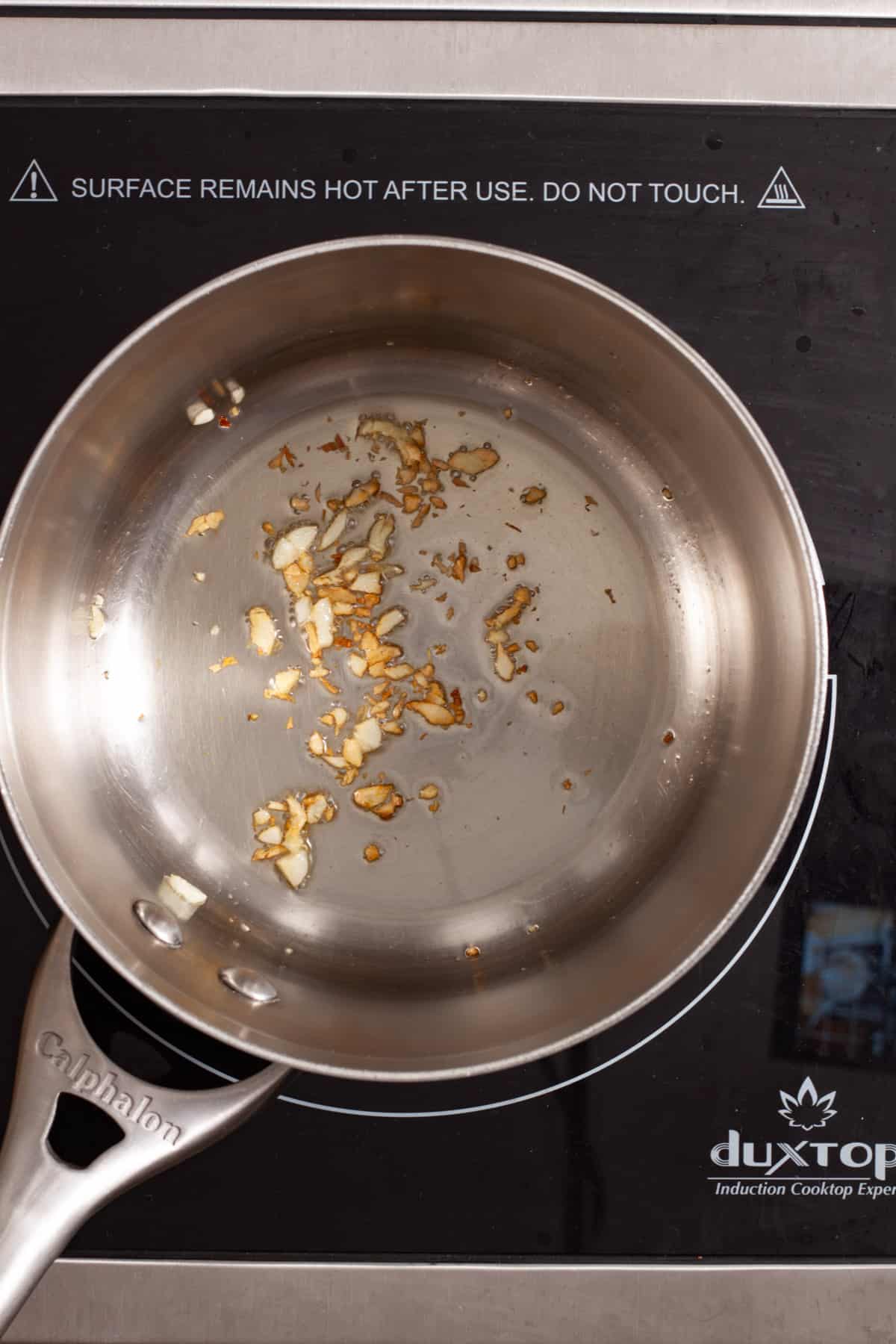Minced garlic cooking in a small saucepan.