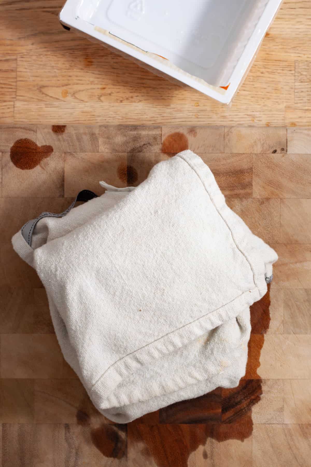 A towel wrapped around a block of extra firm tofu.