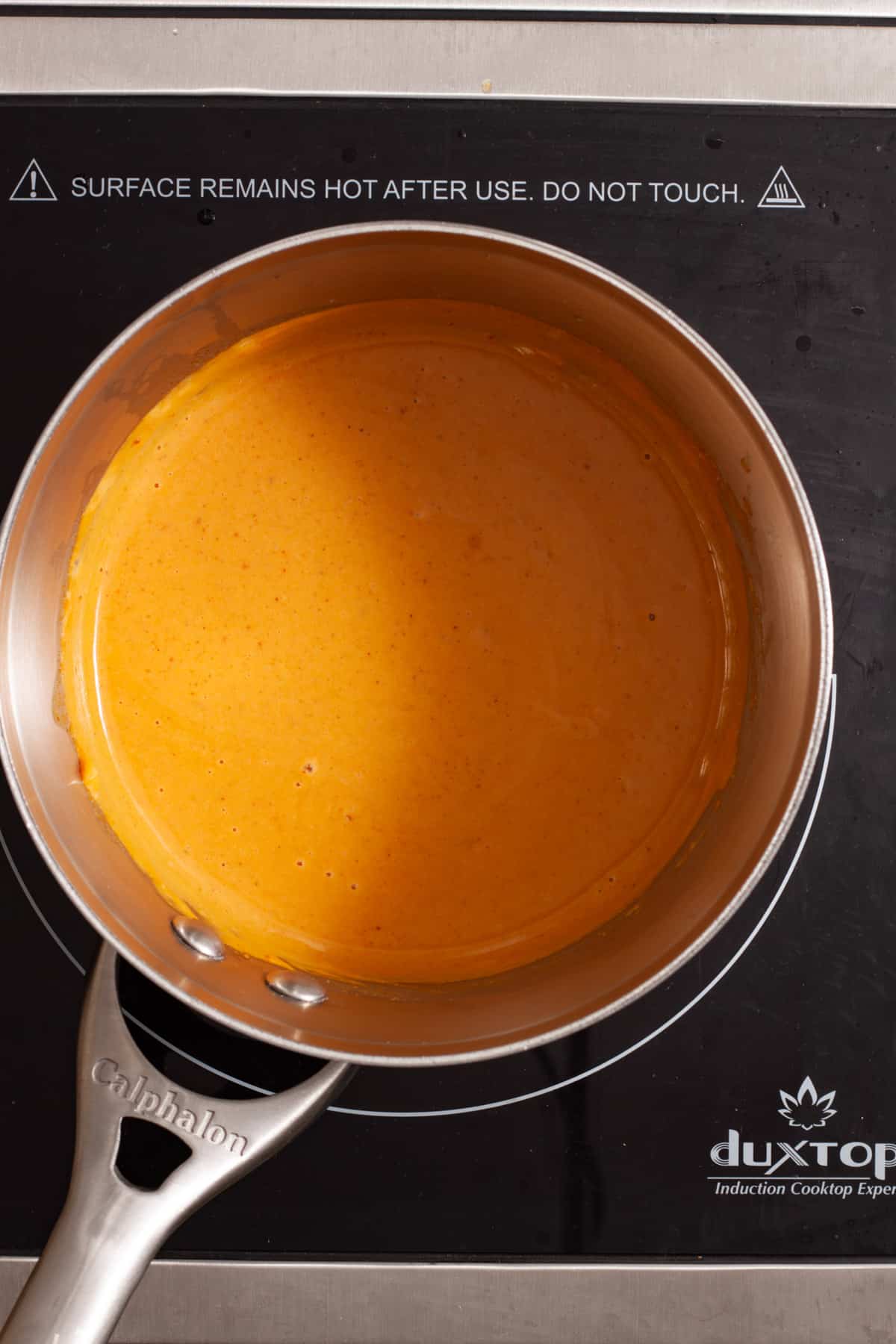 A smooth peanut sauce cooking in a small saucepan.