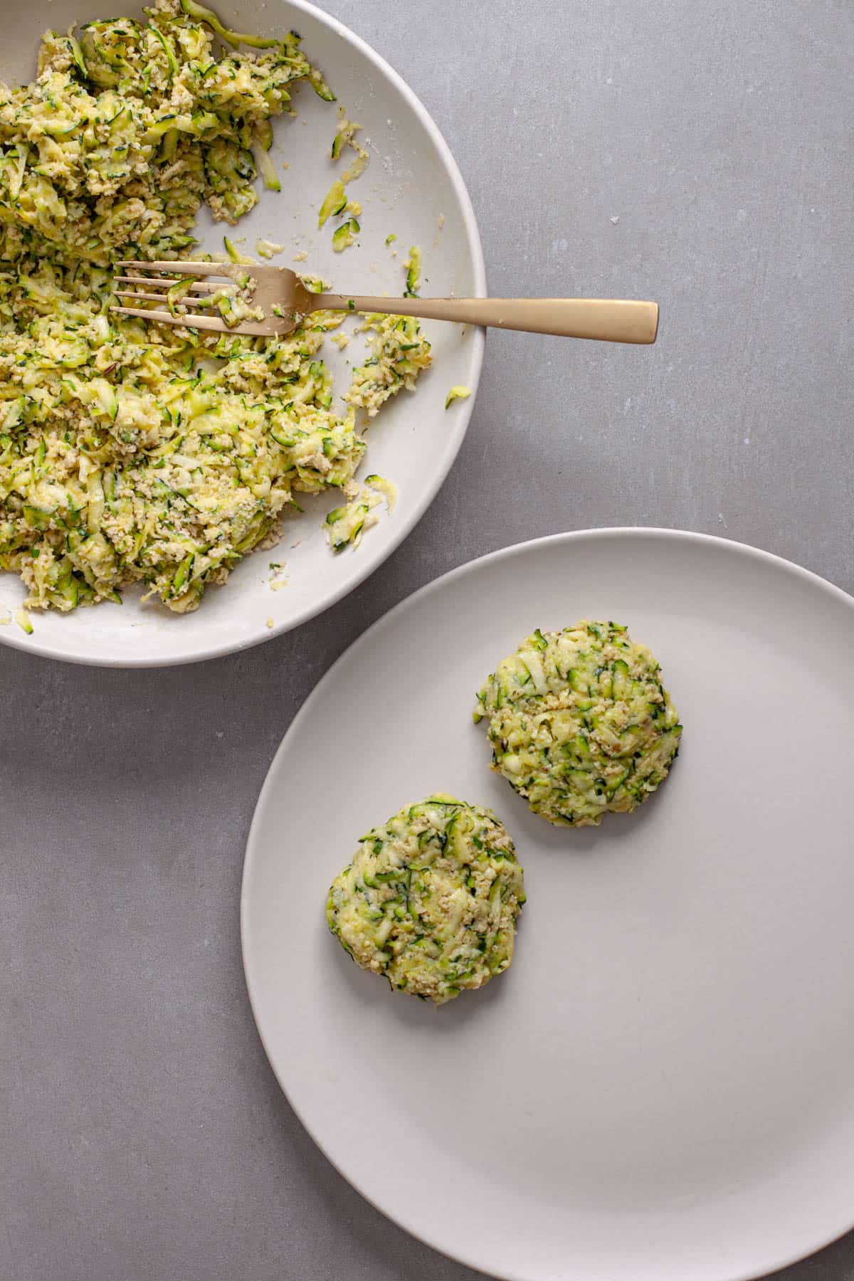 Shredded zucchini getting formed into patties for fritters.