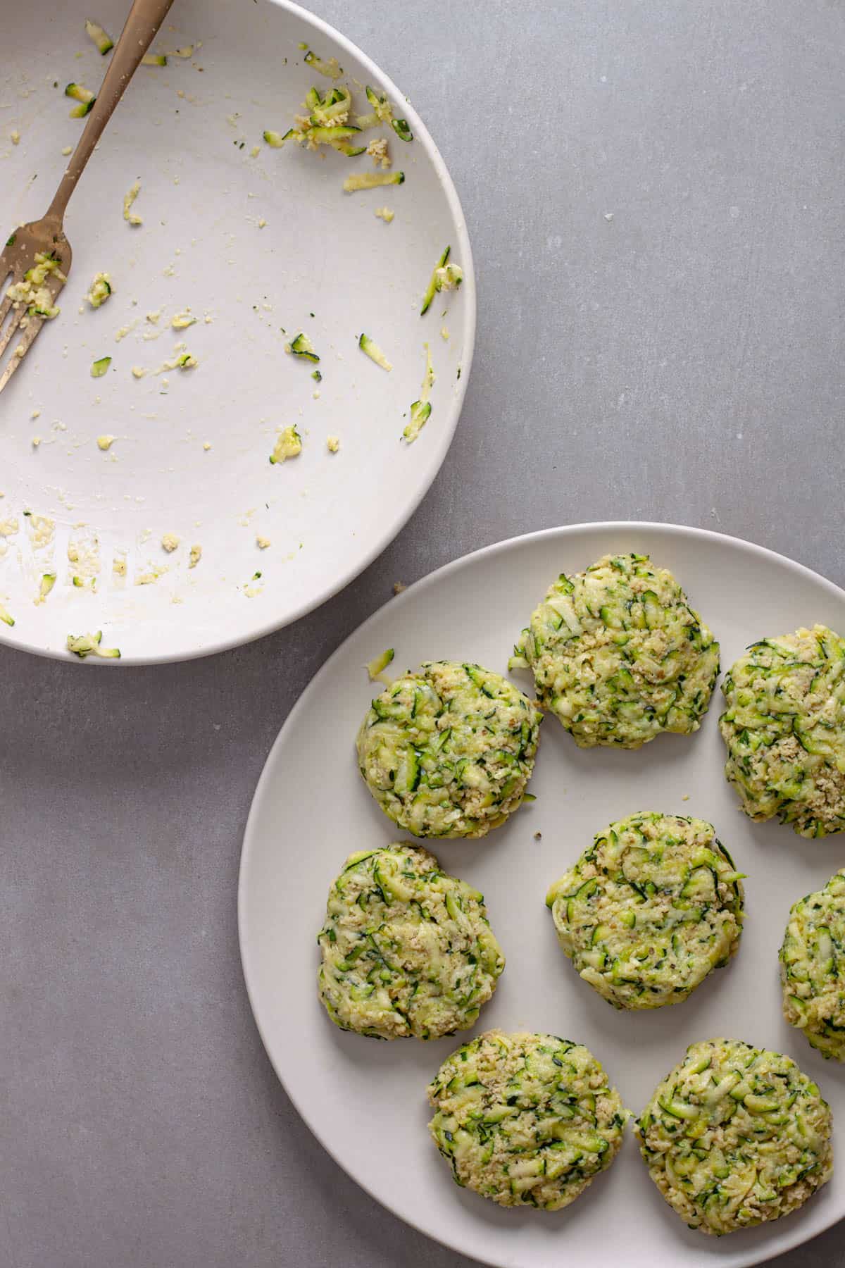 Uncooked zucchini fritters on a white plate.