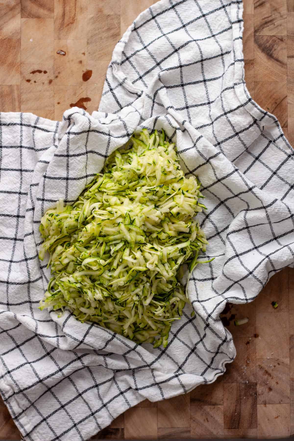 Grated zucchini on a clean kitchen towel getting ready to be rung dry.